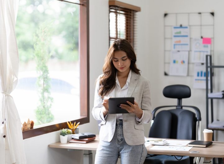 Woman accountant using calculator and digital tablet computer in office, finance and accounting