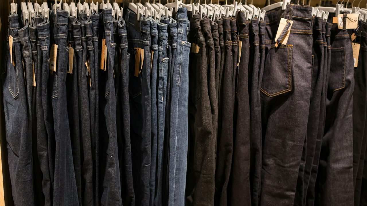 Jeans on clothes rail in clothing store at shopping mall.